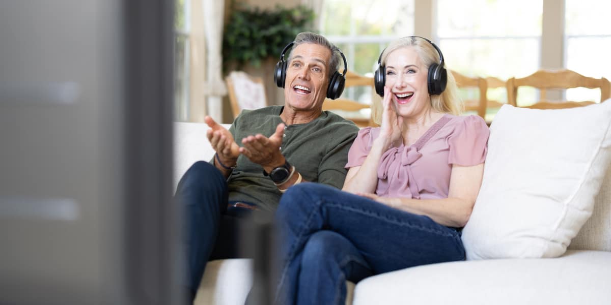 Happy couple watching TV with Avantree Opera Wireless Headphones