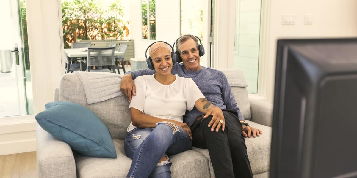 Happy couple watching TV with Avantree Duet Wireless Headphones